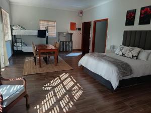 a bedroom with a bed and a table and a chair at Cape Karoo Lodge in Riversdale