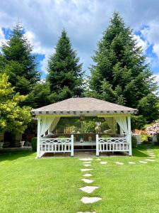 a white gazebo in a yard with trees at Tre Bujtinat Gjinar in Elbasan