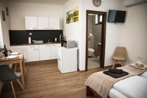 a small kitchen with white cabinets and a bed in a room at Öreg Fűz Apartman in Mosonmagyaróvár