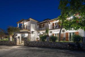 a large white house with a stone wall at Pavlos Maria studios in Skiathos