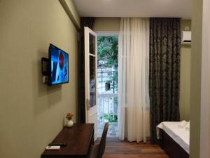 a room with a bed and a television on a wall at Boutique Hotel Iveria in Tbilisi City