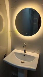 a bathroom with a sink with a round mirror at Hotel shree lodging in Jogeshwāri