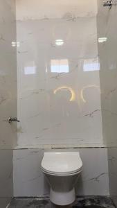 a white toilet in a bathroom with marble walls at Hotel shree lodging in Jogeshwāri +2 photos