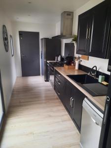 a kitchen with black cabinets and a wooden floor at Suite avec Jacuzzi - Clim - Terrasse - Wi-Fi in Agde
