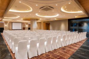 a conference room with white chairs and a screen at Lords Inn Sanand in Chharodi