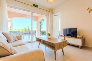a living room with a couch and a tv at Resitour - Aphrodite Beachfront in Pírgos Psilonérou