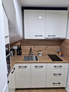 a kitchen with white cabinets and a sink at Holiday house Šadrvan Sarajevo in Hadžići