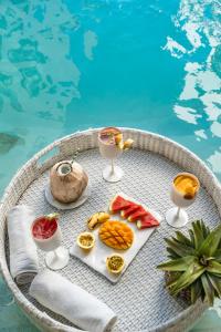 a table with fruit and drinks next to a swimming pool at ZAN Tropical Beach Adults Only in Dimbuni