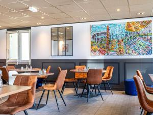 a restaurant with tables and chairs and a painting on the wall at ibis Saint-Denis Stade Ouest in Saint-Denis