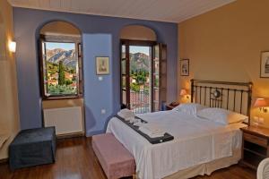 a bedroom with a large bed and two windows at Archontiko Leontari in Leondari