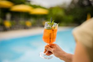 a person holding a drink in front of a pool at Hotel Garni Toscanina - Adults Only in Bad Radkersburg