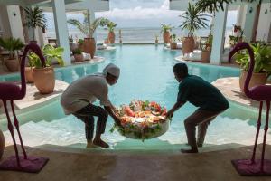 two men holding a basket of fruit in a swimming pool at ZAN Tropical Beach Adults Only in Dimbuni +25 photos