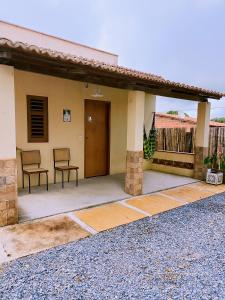 a house with two chairs sitting on a patio at Bom Viver Pousada ltda in Viçosa do Ceará