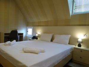 a bedroom with a white bed with two towels on it at Boutique Hotel Iveria in Tbilisi City