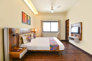 a bedroom with a large bed and a television at FabHotel City Point Executive in Pune