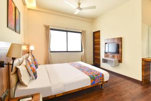 a bedroom with a large bed and a television at FabHotel City Point Executive in Pune