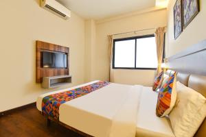 a hotel room with a bed and a television at FabHotel City Point Executive in Pune