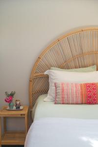 a bed with a wooden headboard next to a table at Studio Thai na praia in Barra de Ibiraquera