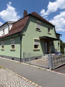 a green house with a fence in front of it at Modern Apartment 1 Graf - New! in Grafenwöhr