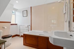 a bathroom with a tub and a sink and a toilet at Keepers Cottage in Dunkeld