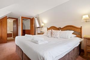 a bedroom with a large white bed with towels on it at Keepers Cottage in Dunkeld