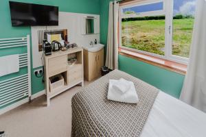 a bedroom with a bed and a sink and a window at The Otter Lodge in Broadford