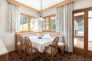 a dining room with a table and chairs and windows at Am Rainell Hof in Ortisei +21 photos