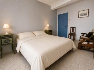 a bedroom with a large white bed and a blue door at La maison boîte à gâteaux in Lapalme