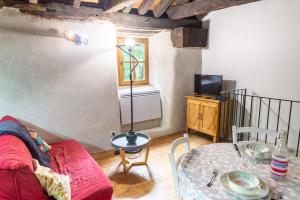 a living room with a red couch and a table at Le gîte du comte 2/3 personnes in Saint-Germain-de-Calberte