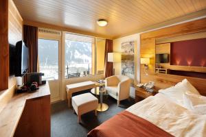 ein Hotelzimmer mit Bett, Schreibtisch und Fernseher in der Unterkunft Eiger Mountain & Soul Resort in Grindelwald