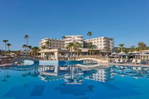 ein Pool in einem Resort mit Palmen und Gebäuden in der Unterkunft Atlantica Ocean Beach Resort in Maleme