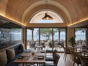 ein Restaurant mit Tischen und Stühlen und einem großen Fenster in der Unterkunft Atlantica Ocean Beach Resort in Maleme