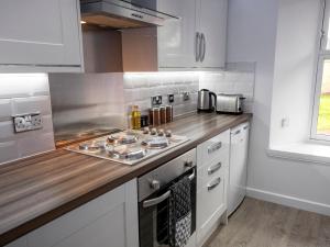 a kitchen with white cabinets and a wooden counter top at 93 King Street in Broughty Ferry