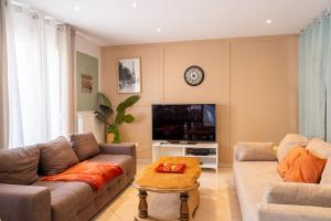 a living room with a couch and a tv at La Maison du Bonheur - Appartements & Chambres à Gisors in Gisors
