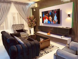 a living room with a large screen tv on a wall at Sheylex Apartments in Idogwari