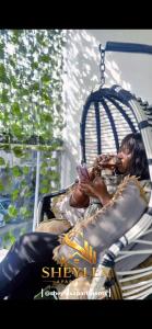 a girl sitting in a crib while looking at her cell phone at Sheylex Apartments in Idogwari