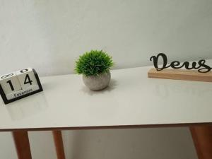 a white table with a clock and a potted plant on it at Refúgio Charmoso 1 in Volta Redonda