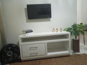 a white dresser with a tv on a wall at Refúgio Charmoso 1 in Volta Redonda +11 photos