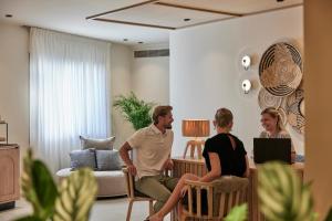 Ein Mann und zwei Frauen sitzen in einem Wohnzimmer. in der Unterkunft Atlantica Ocean Beach Resort in Maleme