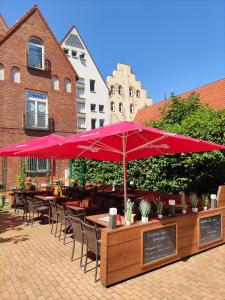 a patio with tables and chairs with red umbrellas at Hotel Am Hopfenmarkt in Rostock
