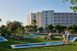 Ein Mann und ein Kind spielen in einem Park in der Unterkunft Atlantica Ocean Beach Resort in Maleme