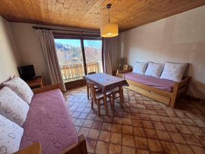 a room with two beds and a table and a window at Studio Ban rouge, Chez Francine in Notre-Dame-de-Bellecombe