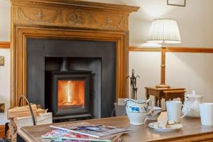 a living room with a fireplace and a wooden table at Jock Scott Cottage in Dunkeld
