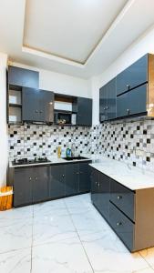 a large kitchen with blue cabinets and white tiles at Moonlight heaven suites in Limbe