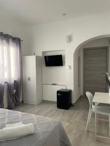 a bedroom with a bed and a table and a tv at Sole & Mare Rooms Briatico in Briatico