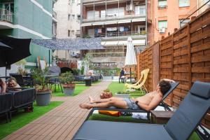 a shirtless man sitting in a chair on a patio at Onefam Les Corts in Barcelona