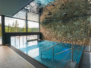 an indoor swimming pool with a rock wall at TRIFORET alpin resort by Falkensteiner in Hinterstoder