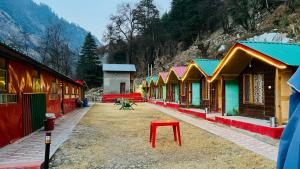 a row of colorful buildings with a red stool at Mahi camping in Jagatsukh