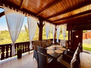 a porch with a table and chairs and windows at Kuća za odmor Srce in Slavetić