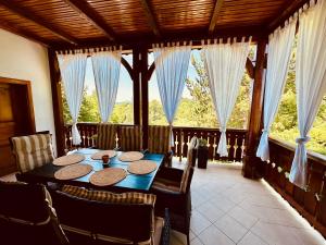 a dining room with a table and some windows at Kuća za odmor Srce in Slavetić